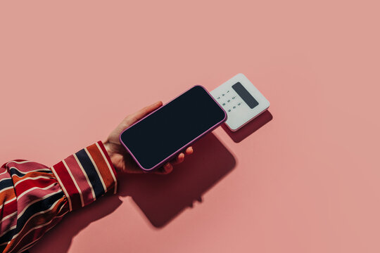 Contactless payment by smartphone at terminal with red shirt on pink