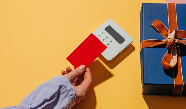 Contactless payment with card and gift box on yellow background