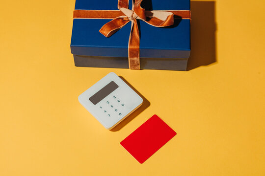 Gift box with contactless payment terminal and card on yellow background