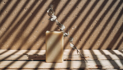 Generated image. Soap and branch placed on wooden surface with light and shadow patterns on warm wall