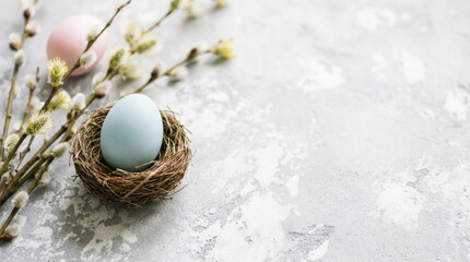 Easter egg in a nest with willow branches and another egg on a textured surface suggesting a spring celebration or decoration