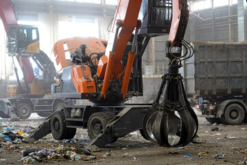 Grappling machine operates in a recycling plant, picking up and sorting through various types of...