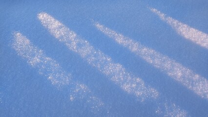 Sunlight on Fresh Snow. Soft sunlight casts gentle shadows on a pristine layer of snow, creating sparkling patterns. The snow appears untouched, highlighting its natural beauty.