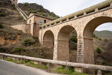 Fototapeta premium Stone bridge with arches and hillside background.. Pueblo de Patones de Arriba in Madrid, known for its slate architecture and for evading the French invasion.