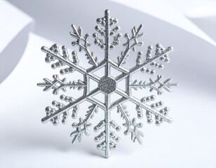 Silver snowflake ornament on white surface with curved paper backdrop