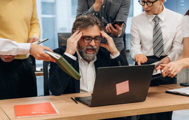 Stressed businessman in a modern office environment overwhelmed by multiple tasks and distractions, showcasing the challenges of workplace productivity and collaboration