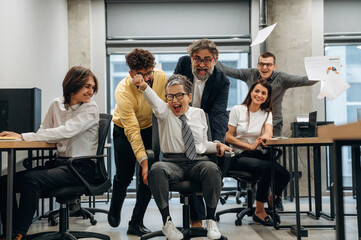 Group of diverse office workers celebrating teamwork and success in a modern business environment, showcasing joy and collaboration in the workplace