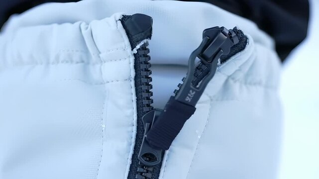 Close-up of a black zipper on white fabric, detail shot.