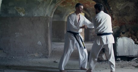 Two karate practitioners train to combine punches and kicks in combat.