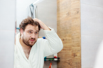 A bearded Caucasian young man washes his face in the bathroom.