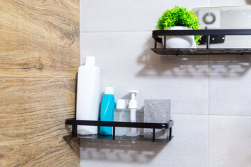 Modern floating bathroom shelves with a black metal frame, bottled cosmetics and a potted plant.