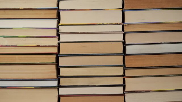 Books Stacks Build Stop Motion, Horizontal stacks of hardcover volumes showing page edges background, Multiple books arranged flat, visible paper blocks, studio lighting, symmetrical layout