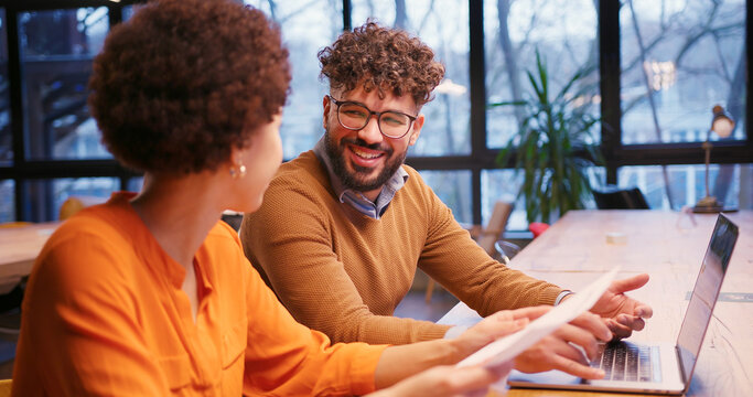 Businesswoman and businessman working together in modern office, analyzing documents, using laptop - Powered by Adobe