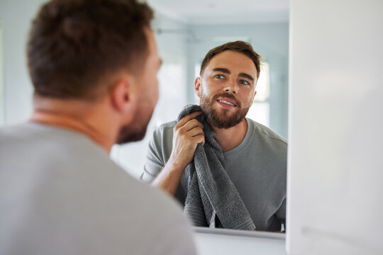 Mid adult man looking at mirror during morning routine