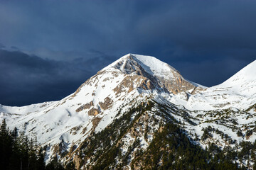 Mt. Vihren summit in winter time. Snow covered peak under the dark stormy sky before snowfall. Wiew from the ski slope.
