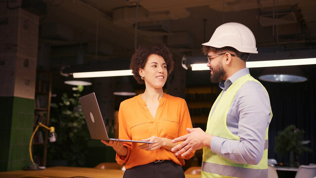 Female architect and male builder in hard hat reviewing building planning on laptop business concept