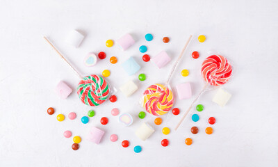 Flat lay with sweets assortment on white. Lollipops, marshmallow and candy drops. Copy space