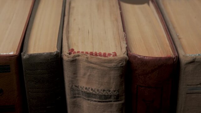 Close up of old hardcover books arranged vertically with visible page edges, Old hardcover books placed side by side showing paper edges, bindings and worn surfaces