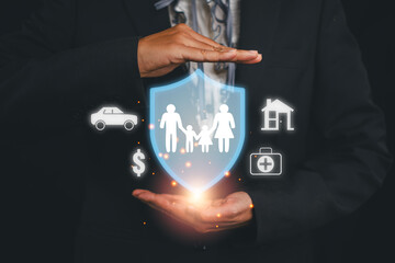 Businessperson holding a digital shield with icons symbolizing family protection, financial security, and home safety.