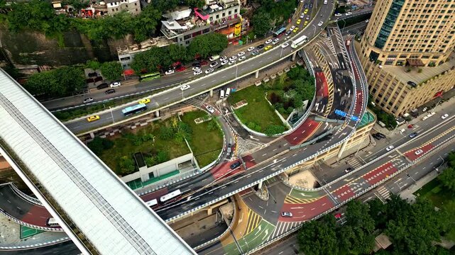 Aerial view of highways with colorful lanes and buildings, contrasting with green patches and moving vehicles, Chongqing, Chongqing, China.