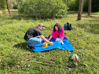Happy couple enjoying a romantic summer picnic in a sunny park, eating watermelon.
