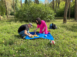Couple enjoying a relaxing picnic on a blue blanket in a sunny park