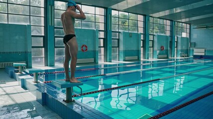 the swimmer comes to the pool and jumps into the water. a swimming athlete trains in the pool, swims under the supervision of a coach. - Powered by Adobe