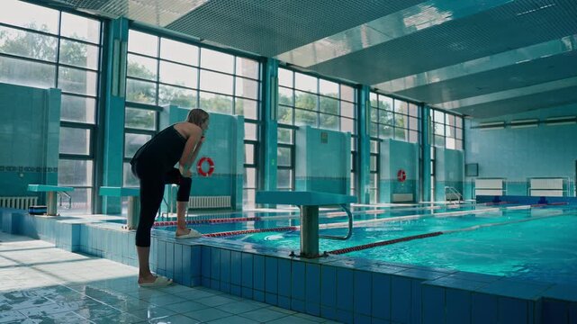 trainer contrasts swimmer's jump into pool. a swimming athlete trains in the pool, swims under the supervision of a coach.