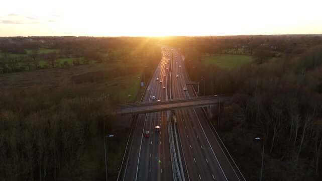 Aerial view of the M42 motorway at sunrise, with vehicles moving along the road, surrounded by trees, Solihull, England, United Kingdom.