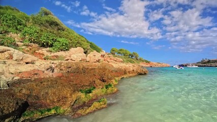 PORTOCOLOM, MALLORCA, SPAIN - OCTOBER 24, 2025: Clear water and rocky shores of Cala Marsal in Portocolom, Mallorca on a sunny day, beautiful coastline and colors