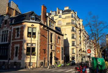 Residential architecture stands in Paris, France. Street corner in the 17th district features a historic brick mansion and classic stone buildings with public bicycles