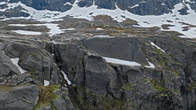 Rocky cliff formations near Trolltunga hiking area in Norway. Snow patches and sharp edges show rugged alpine terrain in early summer.