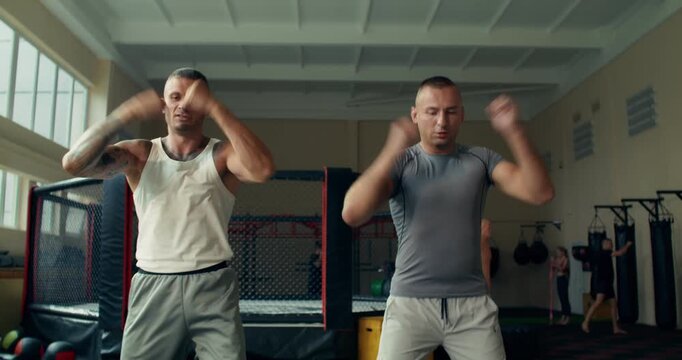 Two MMA fighters do warm-up exercises for their arms before training. .