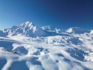 Aerial view of a snow-covered mountain. Sunny and bright day under a blue sky.