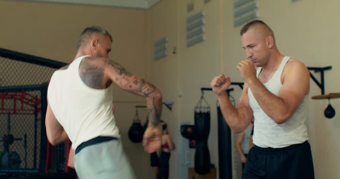 Close-up of two mixed martial artists practicing combination strikes .