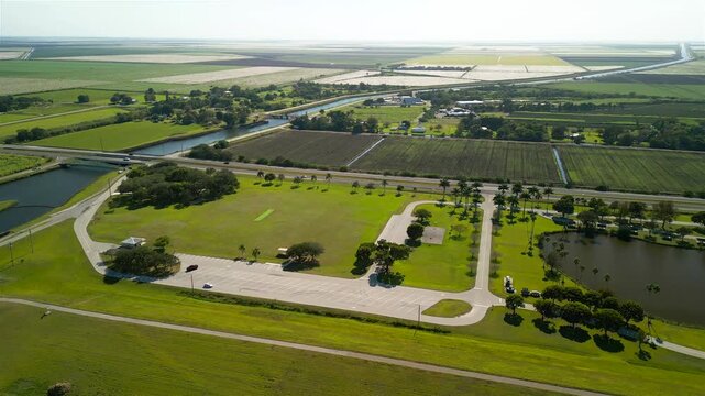 Aerial view of a vibrant green park contrasting with the geometric patterns of cultivated fields and waterways, Lake Okeechobee, Florida, United States.
