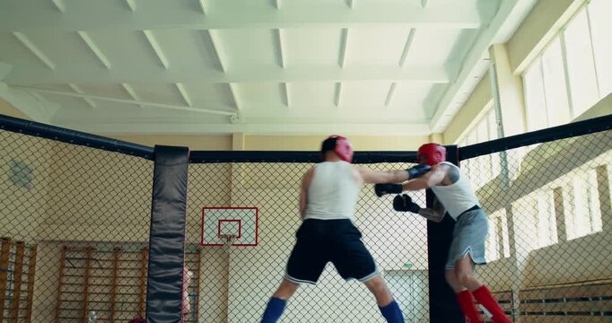 Two fighters practice attacking strikes during sparring . Two MMA fighters spar in the ring.