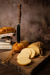 Provolone cheese, wonderful smoked provolone cheese on rustic wood and accessories, abstract background, selective focus.