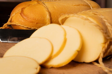 Provolone cheese, wonderful smoked provolone cheese on rustic wood and accessories, abstract background, selective focus.