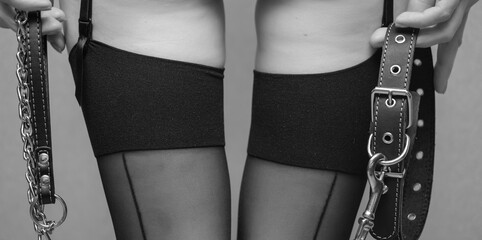 black stockings on women's legs and a collar in her hand