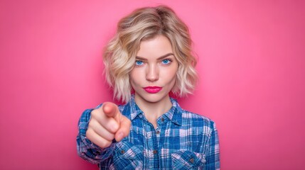 Woman pointing at the camera against a pink background in a studio setting