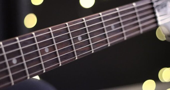 Zoom in shot of black frets fretboard acoustic, electric guitar string on bokeh background