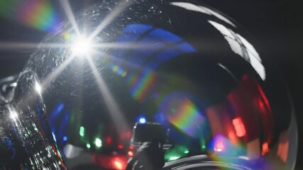 Chrome sphere reflecting colorful lights with lens flare, abstract detail on black background. - Powered by Adobe