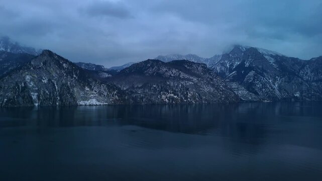 Aerial drone gliding smoothly over alpine mountain range with winter landscape Traunsee Austria