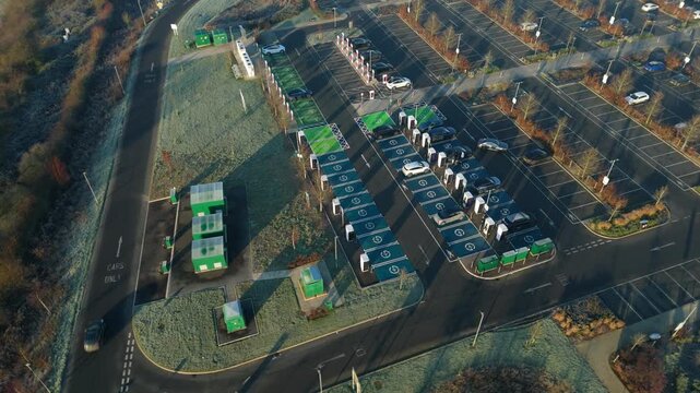 Rugby, United Kingdom - 31 December 2025: Aerial view of rows of parked cars at the EV charging station on a cold day, early in the morning.