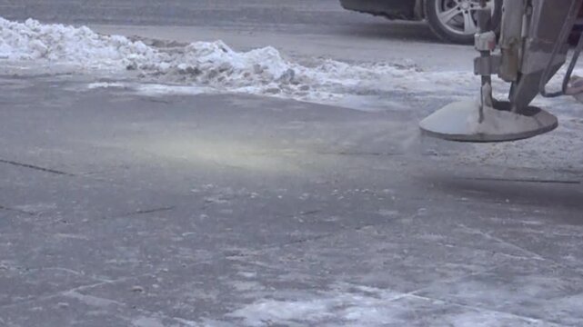 Cleaning of winter streets. Ice, snowfall. A sweeper cleans the sidewalk and the roadway, removal of snow. Super slow motion 1000 fps.