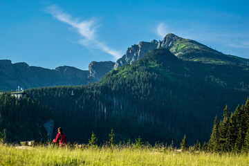 A tourist resting before continuing her journey. In the background are mountains and the cable car to Kasprowy Wierch.