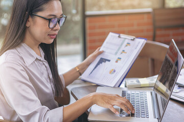 Businesswoman accountant working on desk using laptop for calculate money and checking finance report. Selected focus