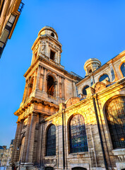 Church of Saint Sulpice stands in the 6th district of Paris, France. Historic stone architecture features the south tower and columns illuminated by golden sunset light