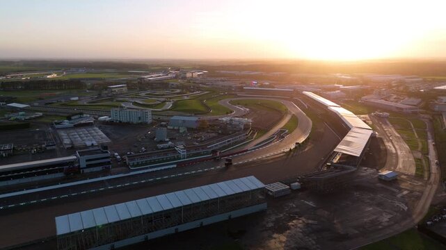 Towcester, United Kingdom - 20 December 2025: Aerial view of the Silverstone Circuit as the sun rises, casting a golden glow over the race track and surrounding buildings.